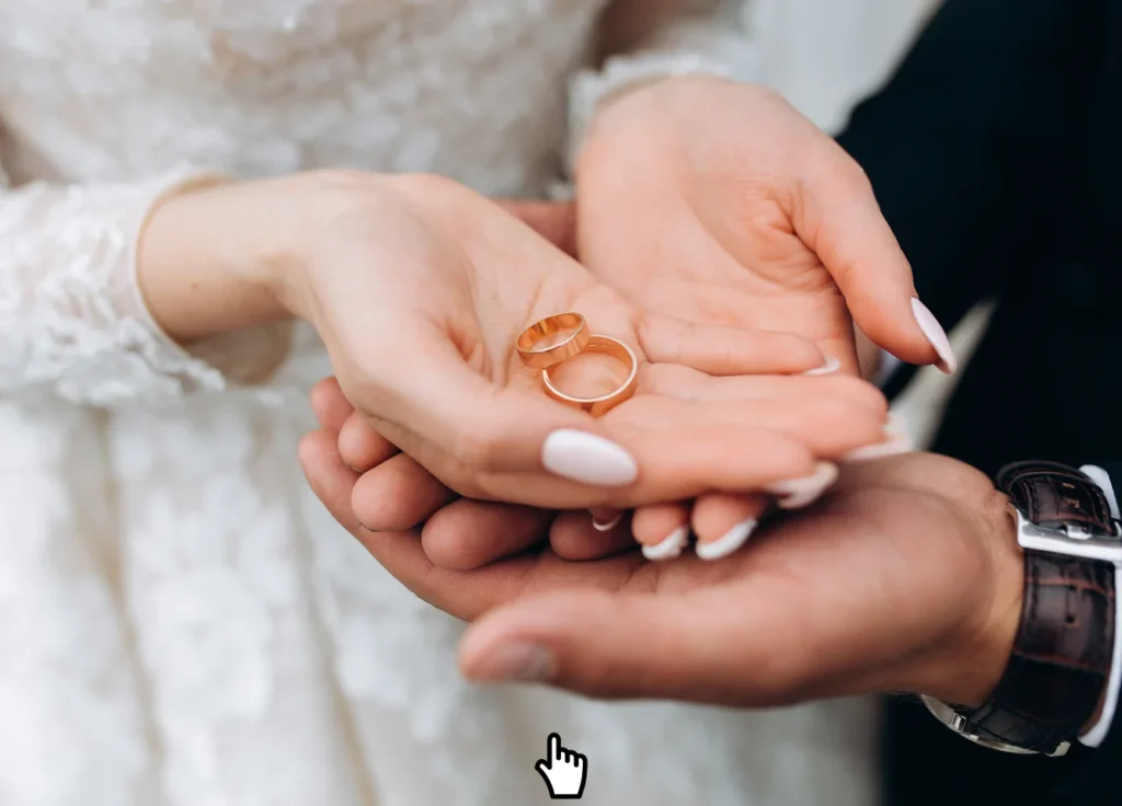 Two gold wedding rings held in the hands of a bride and groom, symbolizing love and commitment during their ceremony.